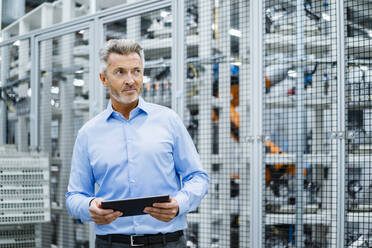 Businessman holding tablet PC at automated factory - DIGF17282