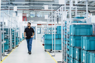 Engineer with hand in pocket inspecting warehouse - DIGF17294