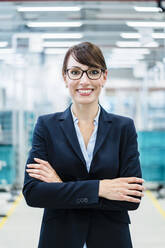 Smiling businesswoman with arms crossed at industry - DIGF17299