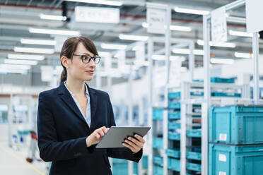 Businesswoman holding tablet PC at automated factory - DIGF17303
