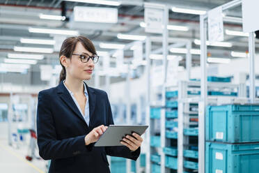 Geschäftsfrau mit Tablet-PC in einer automatisierten Fabrik - DIGF17303