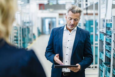 Geschäftsmann diskutiert mit einem Kollegen in der Fabrik über einen Tablet-PC - DIGF17312