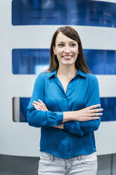 Businesswoman with arms crossed in front of industrial machine - DIGF17318