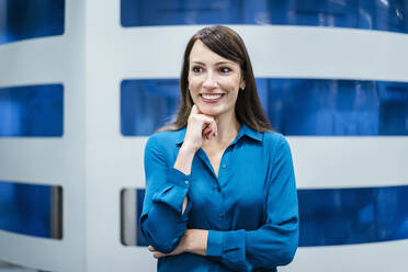 Businesswoman with hand on chin smiling at electrical industry - DIGF17319