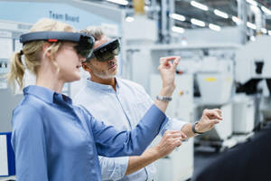 Mitarbeiter diskutieren und benutzen Augmented-Reality-Brillen in einer Fabrik - DIGF17334