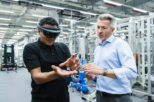 Businessman looking at engineer wearing smart glasses gesturing in factory - DIGF17361