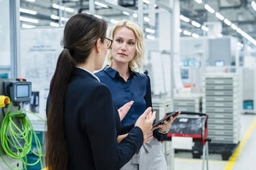 Businesswomen having discussion at automated factory - DIGF17368