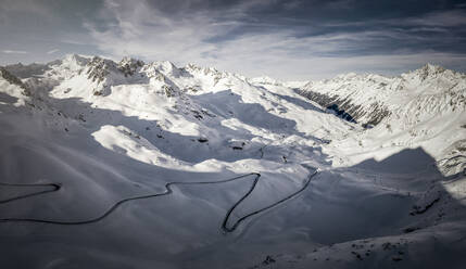 Luftaufnahme der kurvenreichen Straße durch das schneebedeckte Kaunertal in der Abenddämmerung - MALF00388