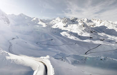 Luftaufnahme der kurvenreichen Straße, die sich über das schneebedeckte Kaunertal erstreckt - MALF00390