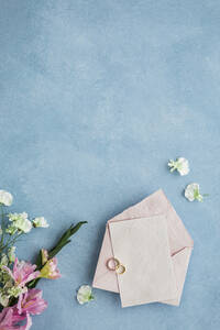 Studio shot of pair of wedding rings, invitation card and flower bouquet - FLMF00734