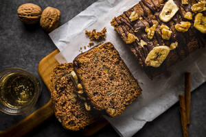 In Scheiben geschnittener Bananenkuchen mit Walnüssen und Schokoladensauce auf dem Schneidebrett - FLMF00767