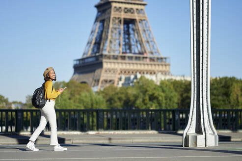 Frau auf der Straße mit Smartphone in der Nähe des Eiffelturms, Paris, Frankreich - KIJF04362