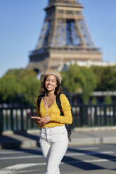 Young tourist with smart phone in front of Eiffel Tower, Paris, France - KIJF04365