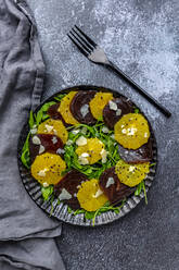 Studioaufnahme eines Tellers mit vegetarischem Carpaccio mit Orangen- und Rote-Bete-Scheiben, Rucola, Parmesan und schwarzem Sesam - SARF04667