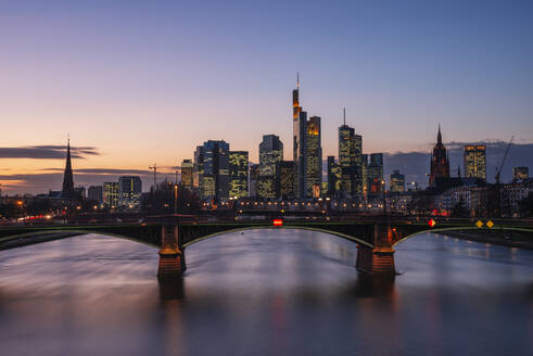 Deutschland, Hessen, Frankfurt, Ignatz-Bubis-Brücke in der Abenddämmerung mit Skyline der Innenstadt im Hintergrund - RUEF03439