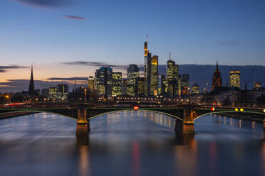 Deutschland, Hessen, Frankfurt, Ignatz-Bubis-Brücke in der Abenddämmerung mit Skyline der Innenstadt im Hintergrund - RUEF03440