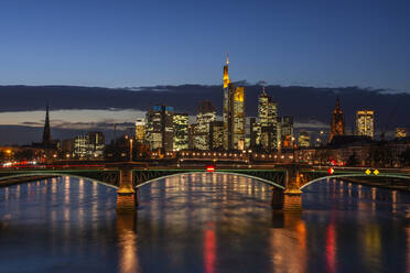Deutschland, Hessen, Frankfurt, Ignatz-Bubis-Brücke bei Nacht mit beleuchteter Stadtsilhouette im Hintergrund - RUEF03441