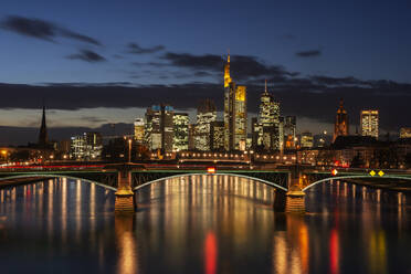Deutschland, Hessen, Frankfurt, Ignatz-Bubis-Brücke bei Nacht mit beleuchteter Stadtsilhouette im Hintergrund - RUEF03442