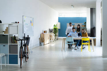 Busy coworkers working on laptop in modern office - GIOF14514