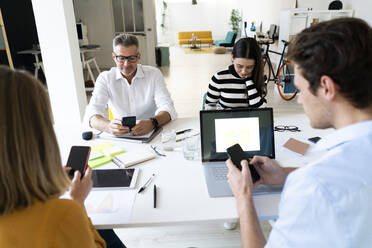 Vielbeschäftigte Kollegen nutzen Smartphones im Büro - GIOF14516