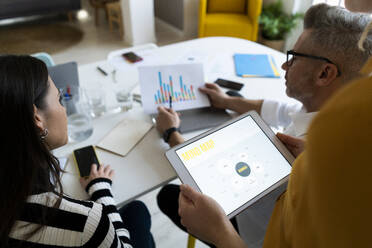 Businessman examining graph report with colleagues at office - GIOF14522