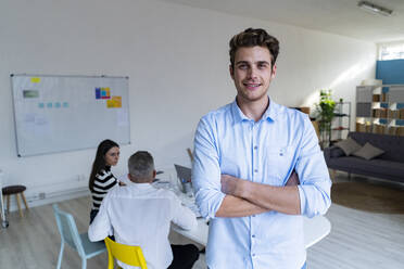 Young businessman with arms crossed in modern office - GIOF14526