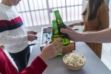 Colleagues toasting beer bottles in office - GIOF14580