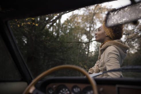 Serene beautiful young woman outside convertible in autumn park - CAIF31811