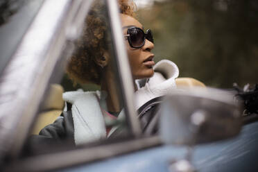 Young woman in sunglasses driving convertible - CAIF31813