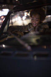 Junge Frau benutzt nachts ihr Smartphone im Cabrio - CAIF31837