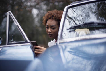Young woman using smart phone in convertible doorway - CAIF31842
