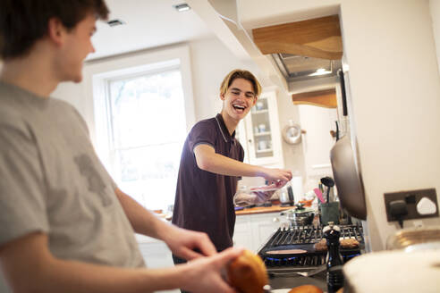 Glückliche Teenager-Brüder beim Kochen in der Küche - CAIF31872