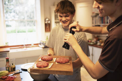 Fröhliche Teenager bereiten in der Küche Hamburger-Patties zu - CAIF31888
