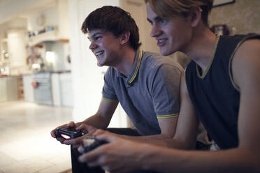 Glückliche Teenager-Jungs spielen zu Hause ein Videospiel - CAIF31889
