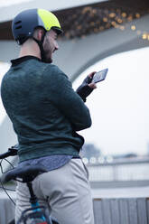 Mann mit Fahrradhelm beim Videochat mit Smartphone - CAIF31899