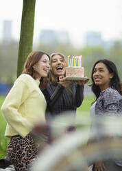 Glückliche junge Freundinnen feiern Geburtstag mit Kuchen - CAIF31907