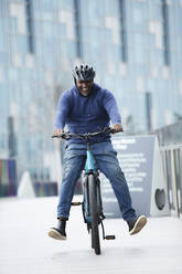 Glücklicher Mann fährt Fahrrad auf dem Bürgersteig - CAIF31911