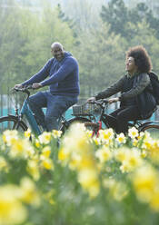 Glücklicher Vater und Teenager-Sohn beim Fahrradfahren im Frühlingspark - CAIF31914