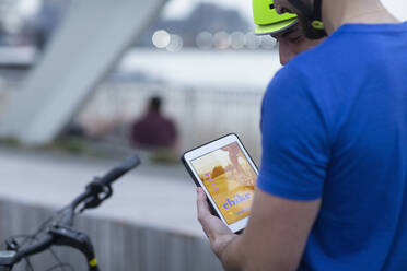 Männer mit digitalem Tablet, die mit einer mobilen App ein Fahrrad mieten - CAIF31918