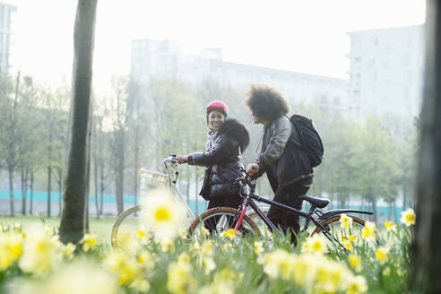 Teen friends with bicycles in sunny urban spring park - CAIF31937