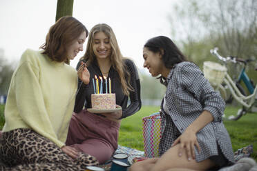 Glückliche junge Frauen Freunde feiern Geburtstag mit Kuchen im Park - CAIF31956