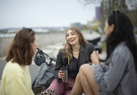 Junge Frauen, die sich in der Stadt unterhalten und Kaffee trinken - CAIF31959