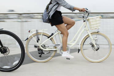 Junge Frau fährt Fahrrad auf einer Brücke - CAIF31960