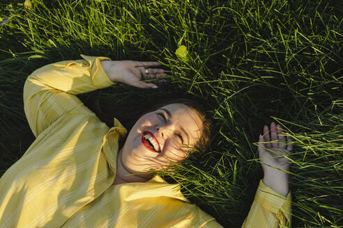 Unbeschwerte Frau liegt lachend im Gras - SEAF00230