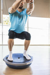 Sportler, der im Fitnessstudio auf einem Balanceball trainiert - IFRF01281