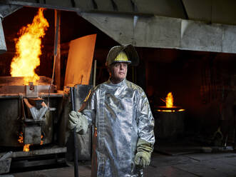 Nachdenklicher Arbeiter mit Helm und Schutzanzug in der Metallindustrie - CVF01758