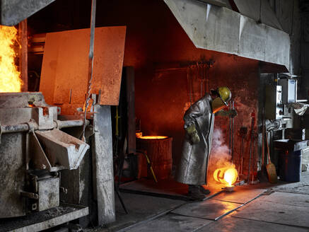 Handwerker, der brennendes Metall gießt, während er in der Industrie arbeitet - CVF01763
