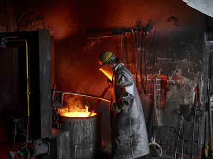 Gießereiarbeiter mit Schutzanzug verbrennt in einem Ofen in der Metallindustrie - CVF01765