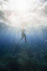 Sunlight on man swimming undersea - RSGF00758