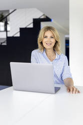 Lächelnde Geschäftsfrau mit Laptop am Schreibtisch - PESF03347